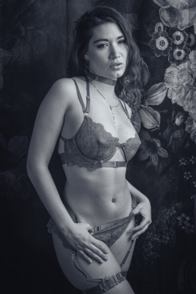 Elena Sartori in lingerie di pizzo davanti al fondale a fiori, in bianco e nero