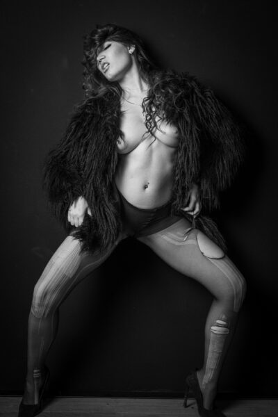 Elena Sartori in pelliccia con la testa all'indietro, gambe divaricate e tacchi, in bianco e nero