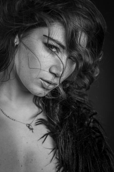 Primo piano in bianco e nero di Elena Sartori con i capelli mossi sul viso e una collana sottile