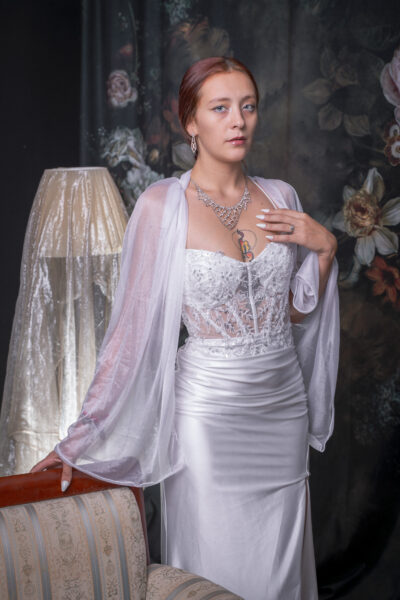 Livia con la mano sul petto accanto a una lampada dal paralume dorato, nello studio fotografico di Trieste