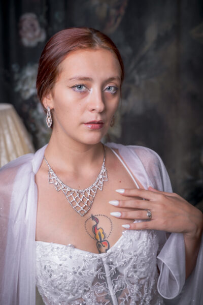 Primo piano di Livia con gli occhi azzurri, collana di strass e mano sul petto