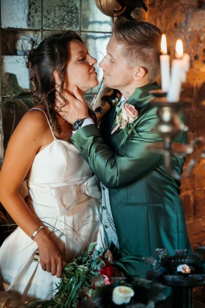 Bacio degli sposi a lume di candela davanti a un muro di mattoni