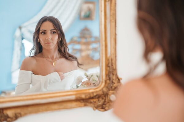 Sposa si guarda in uno specchio con la cornice dorata