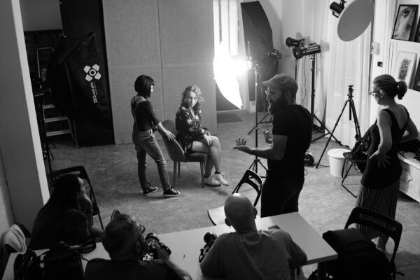 Workshop di ritratto in studio: fotografi e modella sul set con flash e ombrelli, in bianco e nero